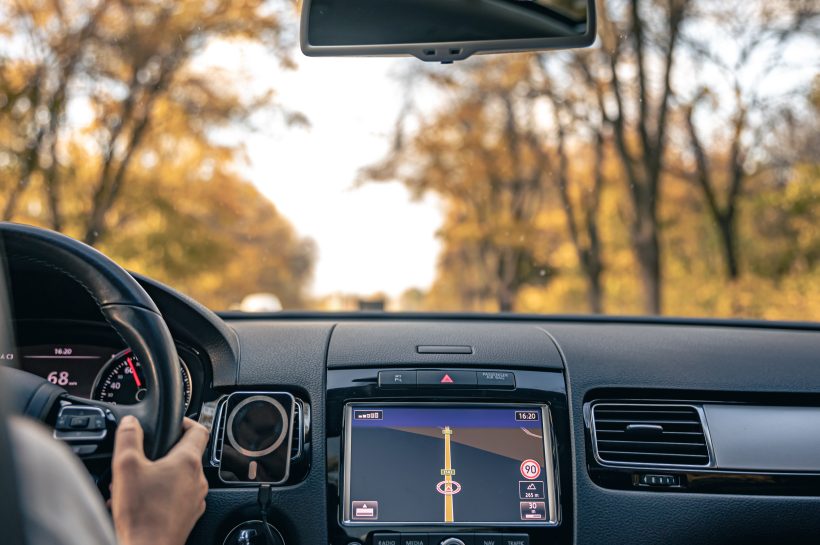 Mazda Navigation via SD Card: Setup, Updates, and Tips A close-up view of a Mazda Connect infotainment system screen displaying a navigation map, with a hand inserting or removing an SD card from its slot, illustrating the process of managing map data for in-car navigation.